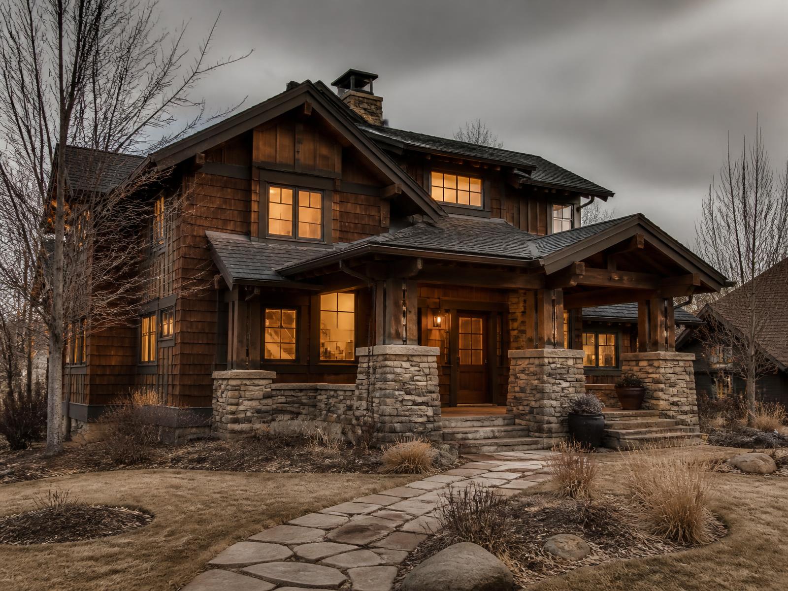 Craftsman home concept photographed head-on, with shingle siding, tapered porch columns on stone piers and a green front lawn